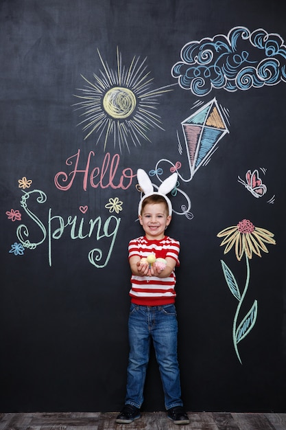 Foto gratuita niño con orejas de conejo y sosteniendo un montón de huevos de pascua