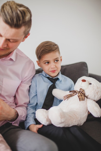 Niño con oso de peluche sentado junto a su padre