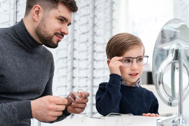 Niño y padre en la tienda probándose gafas