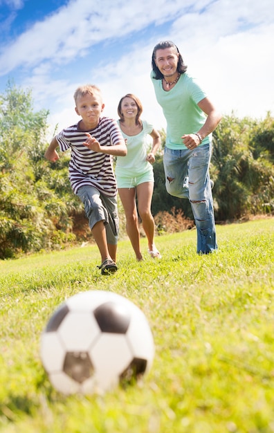 Foto gratuita niño con padres felices jugando en el fútbol