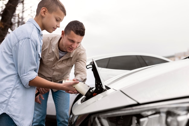 Niño y papá cerca de un coche eléctrico.