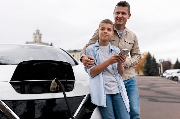 Niño y papá cerca de un coche eléctrico.