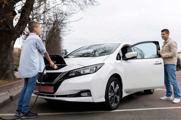 Niño y papá cerca de un coche eléctrico.