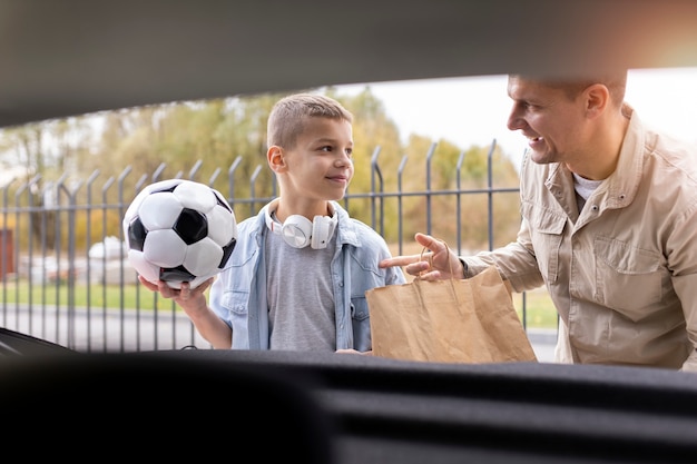 Niño y papá cerca de un coche eléctrico.