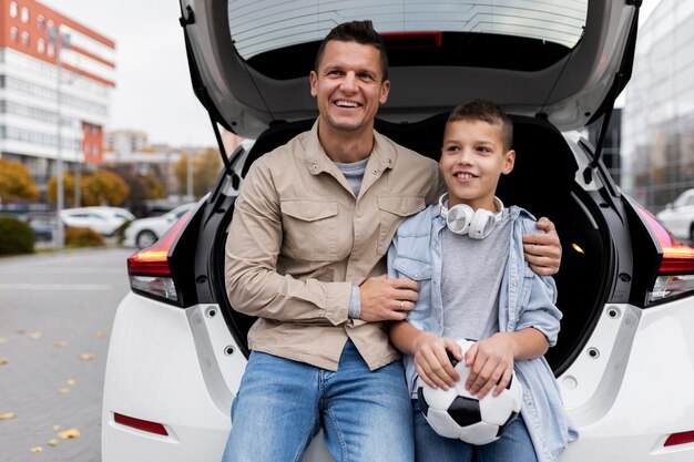 Niño y papá cerca de un coche eléctrico.