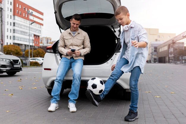 Niño y papá cerca de un coche eléctrico.