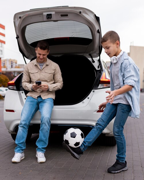 Niño y papá cerca de un coche eléctrico.