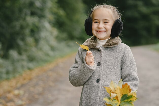 Niño en un parque de otoño. Niño con un abrigo gris.