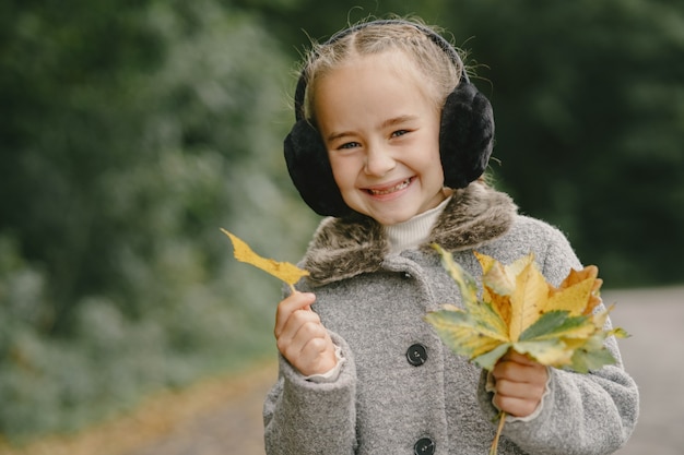 Foto gratuita niño en un parque de otoño. niño con un abrigo gris.