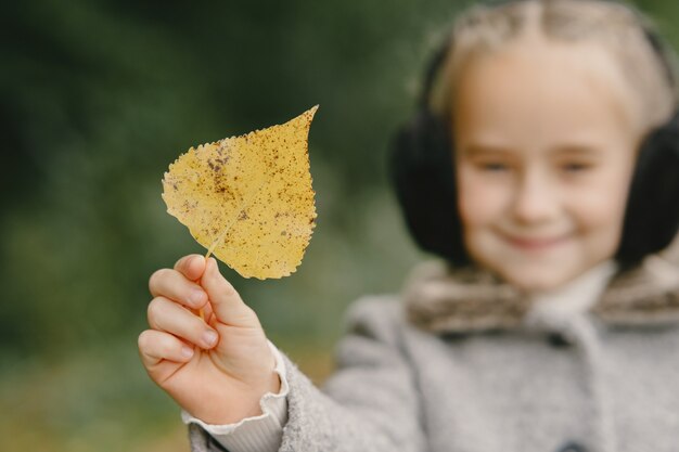 Niño en un parque de otoño. Niño con un abrigo gris.