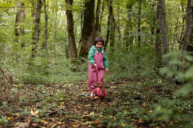 Niño paseando a un perro de tiro completo en la naturaleza