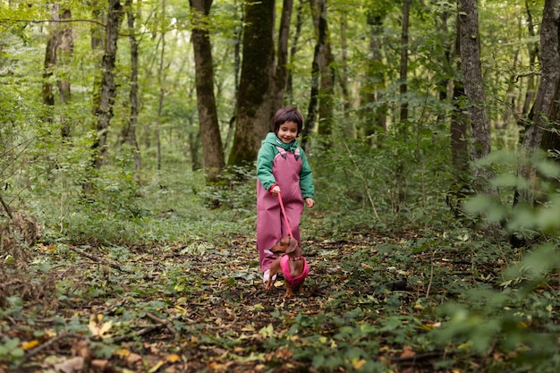 Niño paseando a un perro de tiro completo en la naturaleza