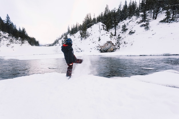 Niño pateando nieve en la orilla del río