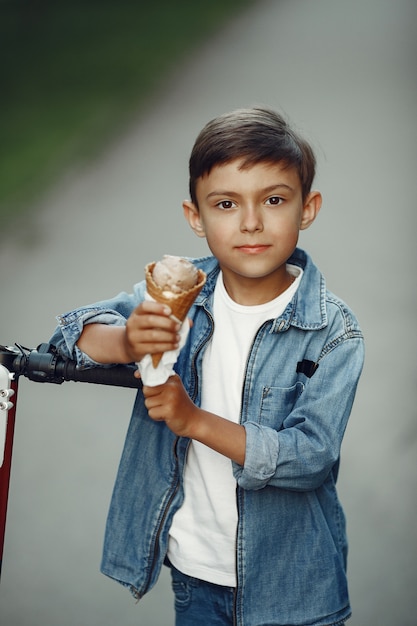 Foto gratuita niño en patinete en el parque. los niños aprenden a patinar. niño patinando en un día soleado de verano.