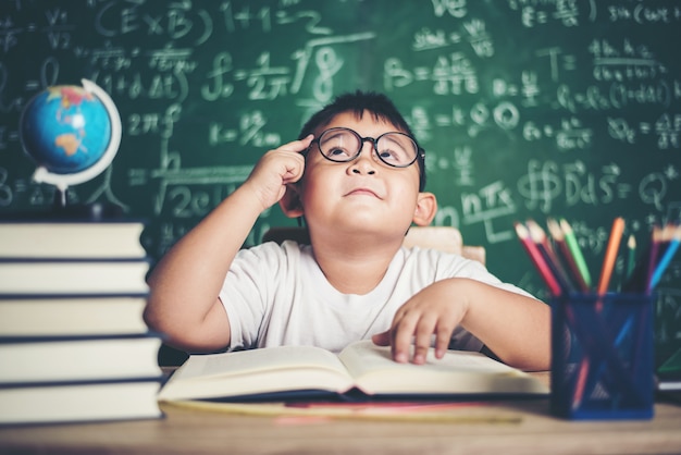 Niño pensativo con el libro en el aula