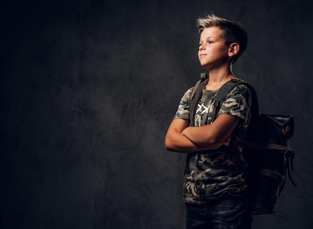 Foto gratuita un niño pensativo está parado en un estudio fotográfico oscuro mientras posa para el fotógrafo.