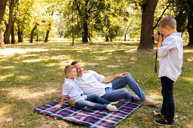 Foto gratuita niño pequeño de alto ángulo tomando una foto de su hermano y padre