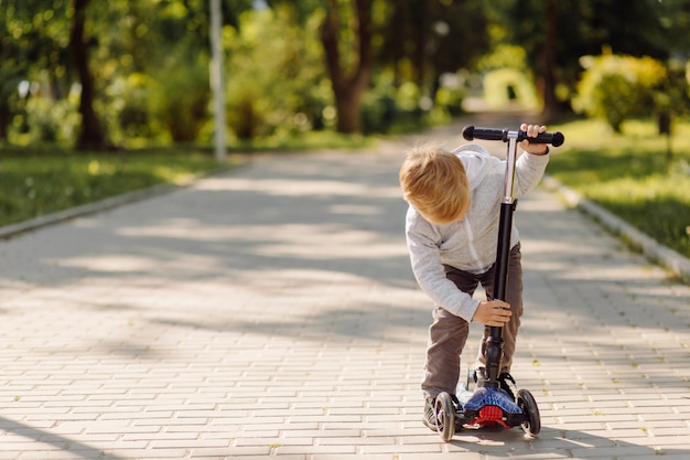 Niño pequeño aprendiendo a andar en scooter al aire libre