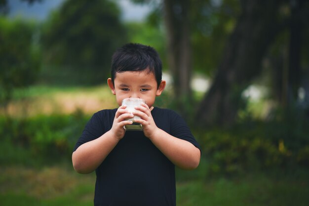 Niño pequeño bebiendo leche en el parque