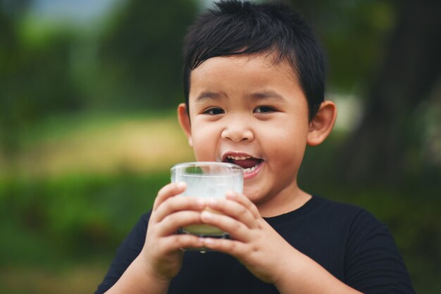 Niño pequeño bebiendo leche en el parque