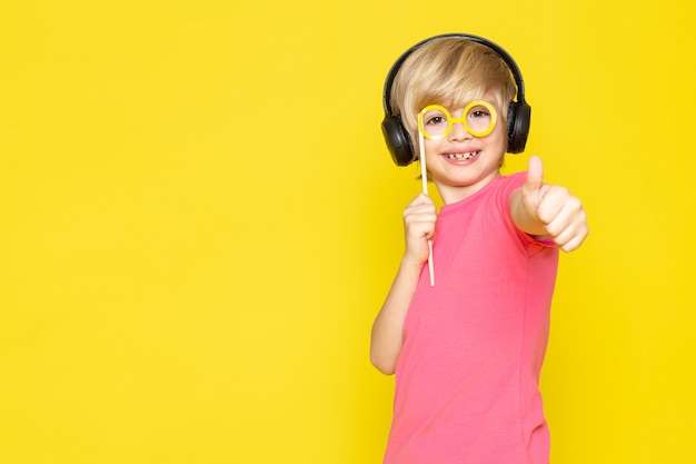 Niño pequeño en camiseta rosa y auriculares negros escuchando música