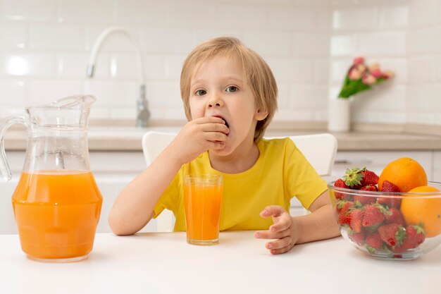 Niño pequeño en casa comiendo frutas