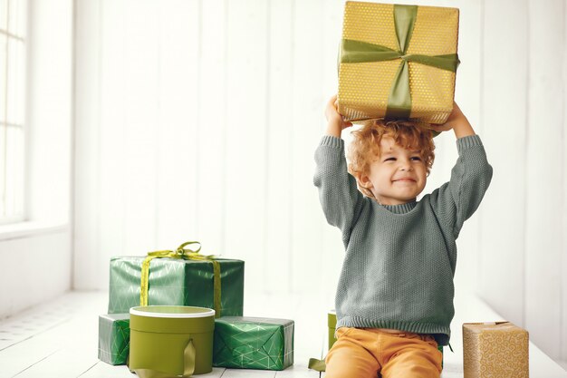 Foto gratuita niño pequeño cerca del árbol de navidad en un suéter gris