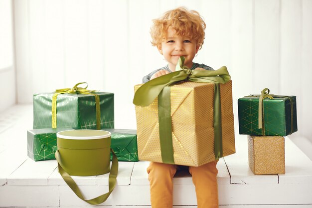 Niño pequeño cerca del árbol de navidad en un suéter gris