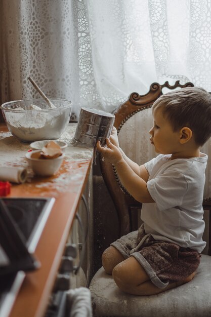 Un niño pequeño en la cocina ayuda a mamá a cocinar. el niño está involucrado en la cocina.