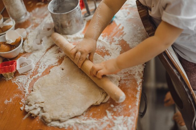 Un niño pequeño en la cocina ayuda a mamá a cocinar. el niño está involucrado en la cocina.