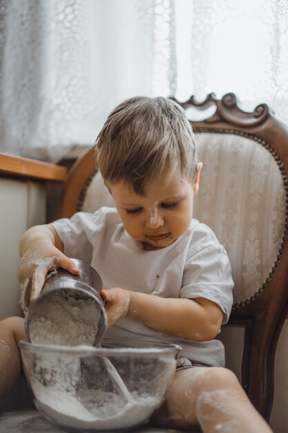 Un niño pequeño en la cocina ayuda a mamá a cocinar. el niño está involucrado en la cocina.