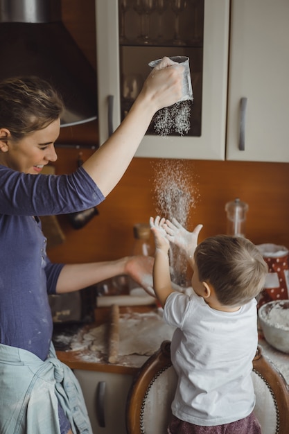 Foto gratuita un niño pequeño en la cocina ayuda a mamá a cocinar. el niño está involucrado en la cocina.