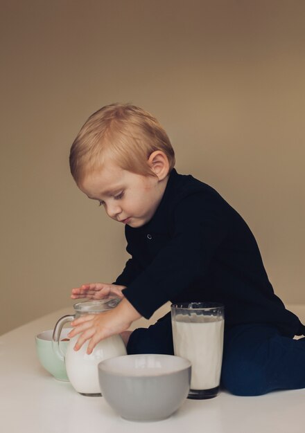 Niño pequeño cogiendo jarra de leche 