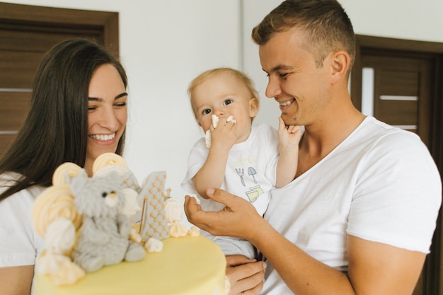 Foto gratuita un niño pequeño come un pastel que le dan sus padres.