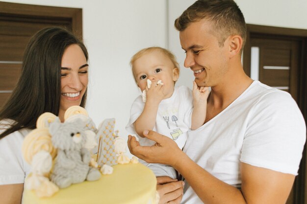 Un niño pequeño come un pastel que le dan sus padres.