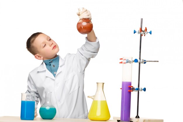 Niño pequeño como químico haciendo experimento con fluido químico en el laboratorio