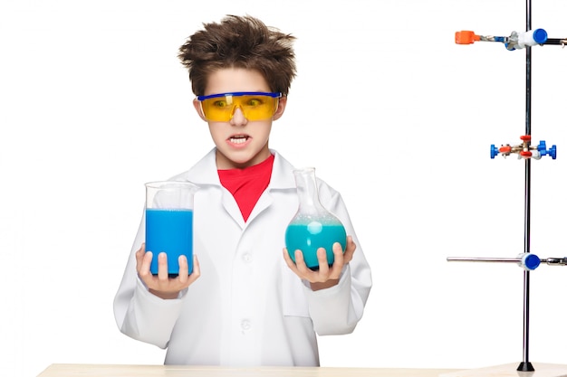 Niño pequeño como químico haciendo experimento con fluido químico en el laboratorio