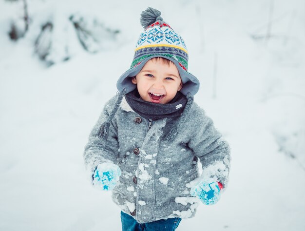 El niño pequeño corriendo a lo largo de la nieve