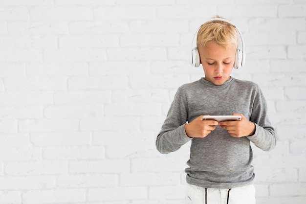 Foto gratuita niño pequeño divirtiéndose con smartphone y auriculares