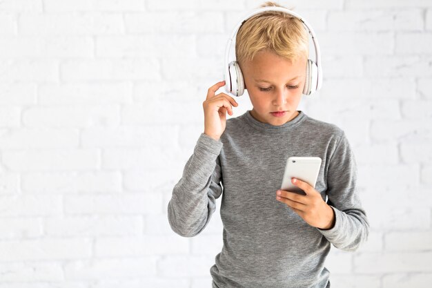 Niño pequeño divirtiéndose con smartphone y auriculares