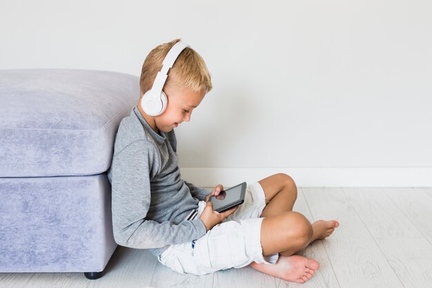 Niño pequeño divirtiéndose con tablet y auriculares