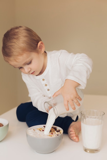 Niño pequeño echando leche a los cereales