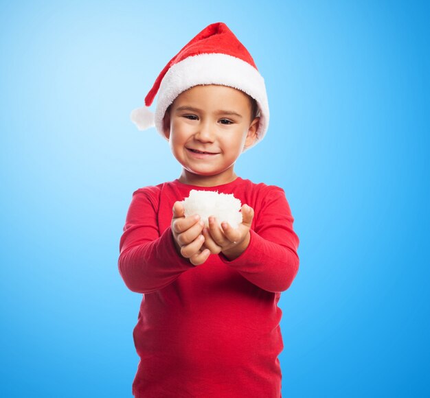 Niño pequeño feliz enseñando nieve