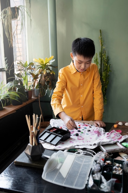 Niño pequeño haciendo proyecto artesanal de bricolaje con camiseta