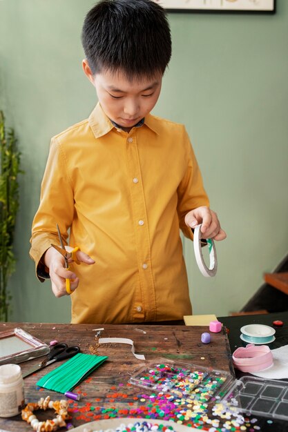 Niño pequeño haciendo un proyecto de bricolaje con materiales reciclados