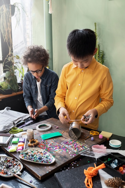 Niño pequeño haciendo un proyecto de bricolaje con materiales reciclados