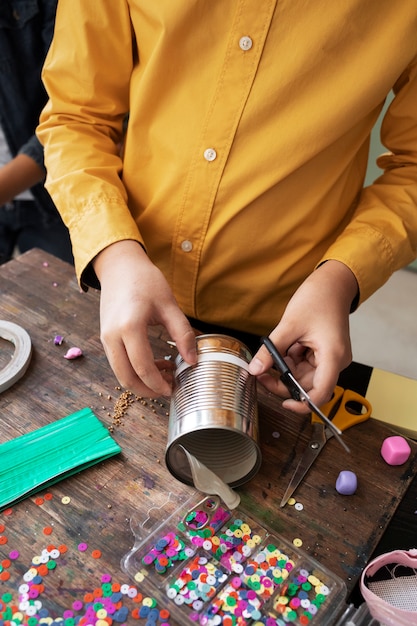 Niño pequeño haciendo un proyecto de bricolaje con materiales reciclados