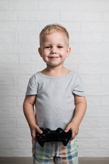 Niño pequeño con joystick en manos en casa
