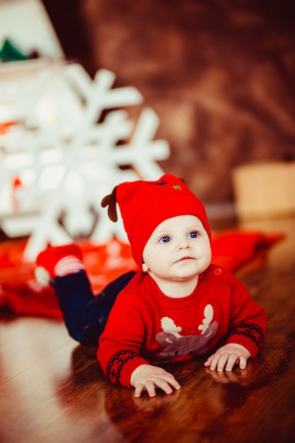 Niño pequeño juega cerca de un árbol de Navidad