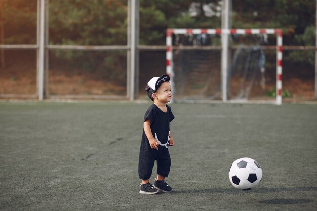 Niño pequeño jugando al fútbol en un campo de deportes